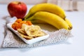 Bowl of dried organic banana chips with fresh bananas in the background Royalty Free Stock Photo