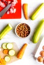 Bowl of dry dogfood, carrot, courgette and meat table background top view Royalty Free Stock Photo