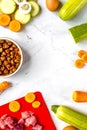 Bowl of dry dogfood, carrot, courgette, meat table background top view mock-up Royalty Free Stock Photo