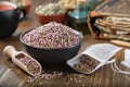 Bowl of dry healthy heather, tea bag with Erica flowers inside. Tea cup, infusion bottle and books.