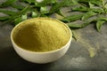 Organic green neem leaves powder in ceramic bowl.