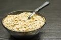 Bowl of dry rolled oat flakes oatmeal on old wooden table Royalty Free Stock Photo