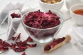 Bowl of dry rose petals, tea bags filled with red petals of heathy rose. Herbal tea cup, teapot and mortar on table