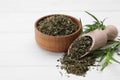 Bowl of dry tarragon, scoop and fresh leaves on white wooden table Royalty Free Stock Photo