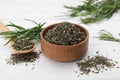 Bowl of dry tarragon, spoon and fresh leaves on white wooden table Royalty Free Stock Photo