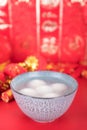 A bowl of dumplings or Yuanxiao on a festive red background. The Chinese characters in the picture mean `happiness`