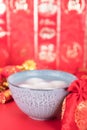 A bowl of dumplings or Yuanxiao on a festive red background. The Chinese characters in the picture mean `happiness`