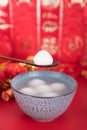 A bowl of dumplings or Yuanxiao on a festive red background with a spoon. The Chinese characters in the picture mean `happiness` a