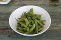Bowl of Edamame, green beans of boiled soybeans on wooden background. Japanese food