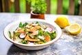 bowl of fattoush with a sprinkle of sumac, lemon beside