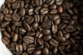 Bowl filled of fresh arabica or robusta coffee beans on a wooden table.