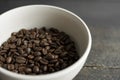 Bowl filled of fresh arabica or robusta coffee beans on a wooden table.