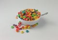 Sugar coated fruity flavored cereal in a bowl with milk and spoon