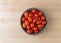 Bowl filled with grape tomatoes on a wood table Royalty Free Stock Photo