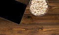 Bowl filled with modern tablet computer and popcorn eaten while watching movies and TV series on wooden floor.