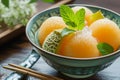 A bowl filled with oranges is placed next to a pair of chopsticks on a wooden table, Bowl of Yubari Melon, luxurious Japanese Royalty Free Stock Photo