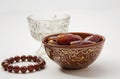 a bowl of dates, a prayer beads, a glass and a copy of the Holy Quran over white background Royalty Free Stock Photo