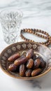 a bowl of dates, a prayer beads, a glass and a copy of the Holy Quran over white background Royalty Free Stock Photo