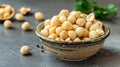 A bowl filled with raw macadamia nuts on a dark surface. Some nuts are scattered around the bowl. The setting Royalty Free Stock Photo
