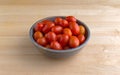 Bowl filled with grape tomatoes on a wood table Royalty Free Stock Photo