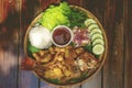 Bowl filled with a variety of cooked fish dishes, positioned in the center of a wooden table