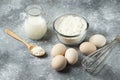 Bowl of flour, eggs and whisker on marble background