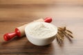 Bowl of flour, wheat ears and rolling pin on wooden table. Space for text Royalty Free Stock Photo