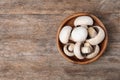 Bowl of fresh champignon mushrooms on wooden background, top view Royalty Free Stock Photo