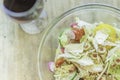 Bowl of fresh cheese vegetable salad and glass of red wine placed on wooden table Royalty Free Stock Photo