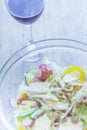 Bowl of fresh cheese vegetable salad and glass of red wine placed on wooden table.Flat layout image with blue tones Royalty Free Stock Photo