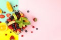Bowl of fresh fruit salad on multicolor background top view