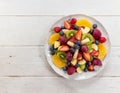 A bowl of fresh fruit salad on a wooden table. Kiwi, oranges, blueberries, bananas. Healthy meal. vegetarian dish Royalty Free Stock Photo