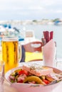 Bowl of fresh Greek salad with feta cheese. Greek salad and beer mug on table against the sea bay background in Greece Royalty Free Stock Photo