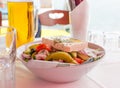 Bowl of Greek salad with feta cheese, green pepper, tomato, olives and red onion. Beer mug and empty glasses on table Royalty Free Stock Photo