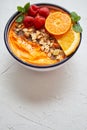 Bowl with fresh healthy smoothie or yogurt. With orange slices, tangerine, raspberry, chia and nuts