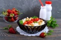 A bowl of fresh home-made cottage cheese with strawberries, mint and nuts on a wooden background. Royalty Free Stock Photo