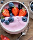 Bowl of fresh mixed berries and yogurt with farm fresh strawberries, blackberries and blueberries served on a wooden table Royalty Free Stock Photo