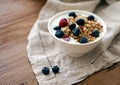 Delicious yogurt breakfast bowl with muesli and fresh blackberries on a wooden table and linen kitchen-towel. Healthy and organic Royalty Free Stock Photo