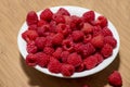 A Bowl of Fresh Picked Raspberries in a White Bowl on a Wooden Board Royalty Free Stock Photo