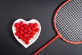 A bowl of fresh raspberries and badminton racket isolated in the black background Royalty Free Stock Photo