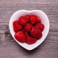 In the bowl fresh raspberries, in the foreground, against the background of rough wood