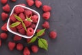 Bowl of fresh raspberries with green leaves on dark beton rock background. Top view Royalty Free Stock Photo