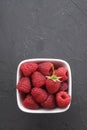 Bowl of fresh raspberries with green leaves on dark beton rock background. Top view Royalty Free Stock Photo