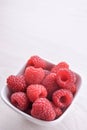 Bowl of fresh raspberries with green leaves on wooden background. Top view Royalty Free Stock Photo