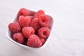 Bowl of fresh raspberries with green leaves on wooden background. Top view Royalty Free Stock Photo