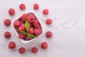 Bowl of fresh raspberries with green leaves on wooden background. Top view Royalty Free Stock Photo