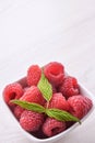 Bowl of fresh raspberries with green leaves on wooden background. Top view Royalty Free Stock Photo