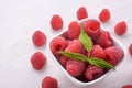 Bowl of fresh raspberries with green leaves on wooden background. Top view Royalty Free Stock Photo