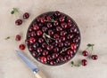 Bowl of fresh red cherries and knife on beige background. Top view Royalty Free Stock Photo