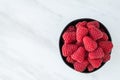 Bowl of fresh red raspberries for dessert, round black ceramic bowl, white marble background Royalty Free Stock Photo